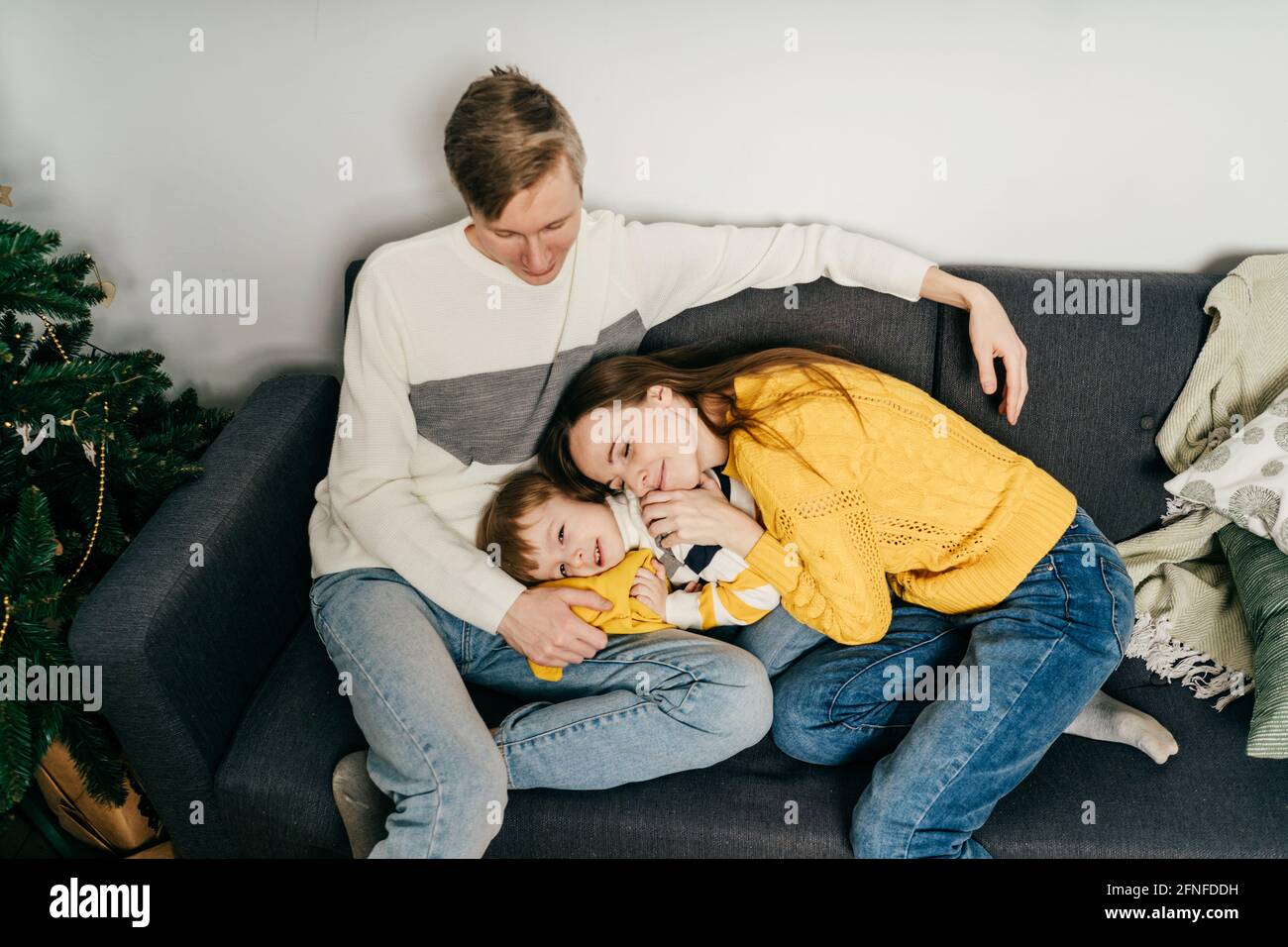Bonne famille mère, père et garçon à la maison dans le canapé. Couleurs jaune et gris. Banque D'Images