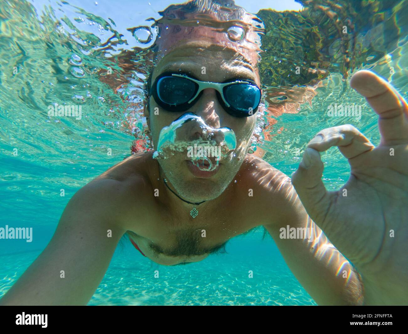 Vue sous-marine d'un plongeur jeune homme nager dans la mer. Des bulles d'air sortant de la bouche et le nez Banque D'Images