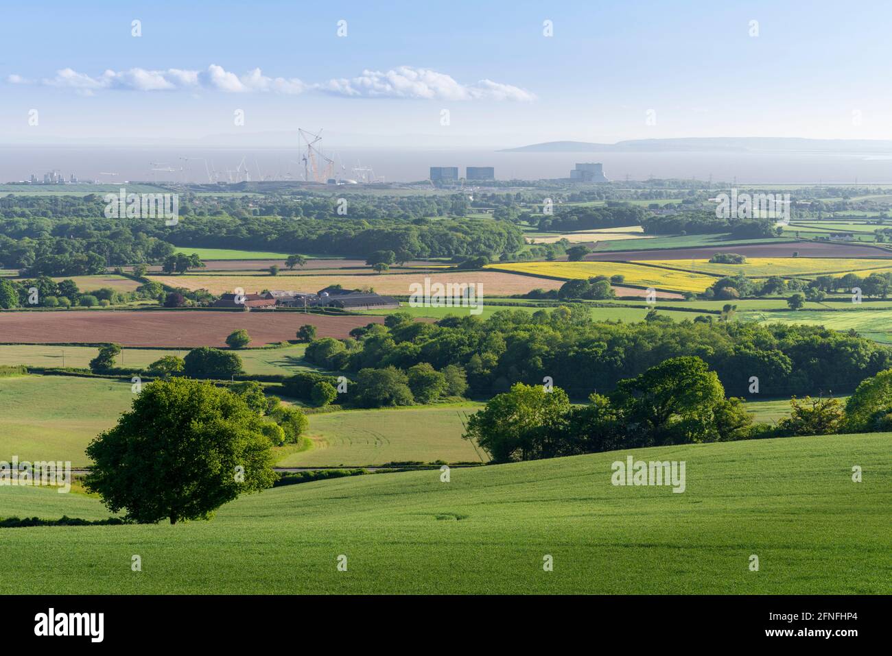 Une vue printanière matinale ensoleillée depuis le pied des collines de Quantock au-dessus de la campagne et de la centrale électrique de Hinkley point sur la rive du Canal de Bristol, Somerset, Angleterre. Banque D'Images