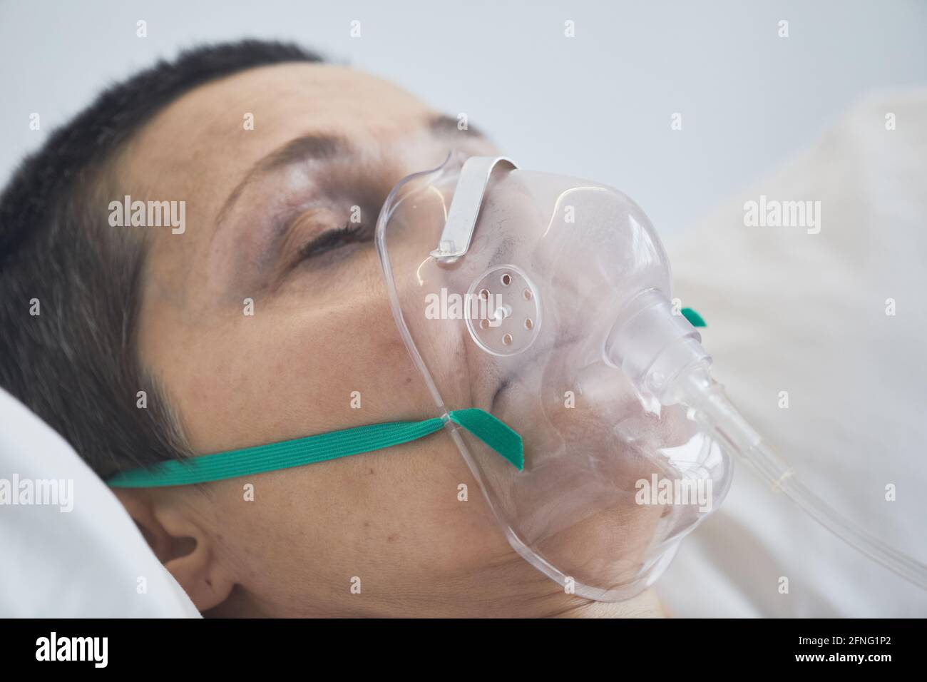 Gros plan de la femme adulte couché sur le lit dans un masque médical pendant le fonctionnement Banque D'Images