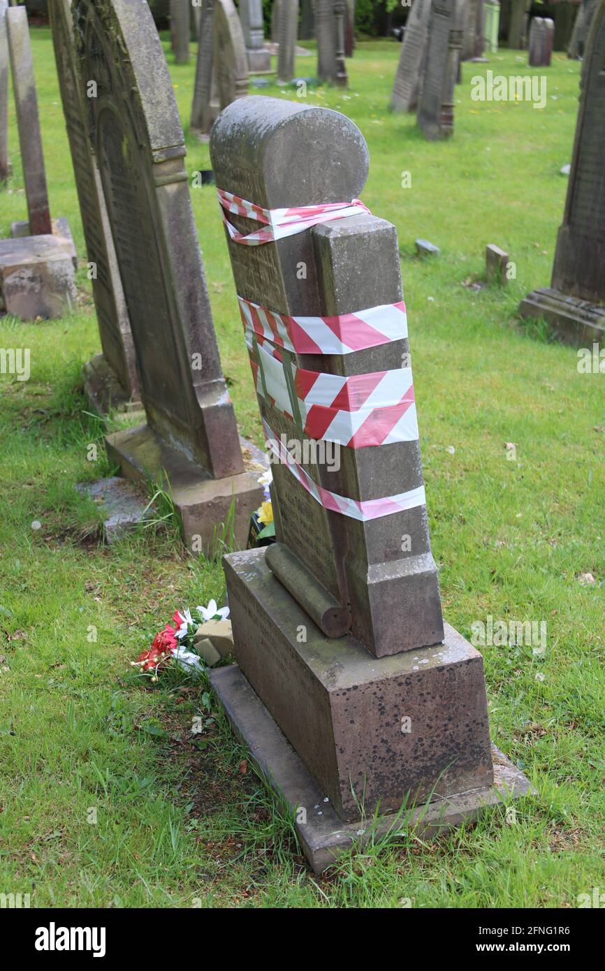 Ruban de sécurité enroulé autour d'une pierre tombale penchée dans une tombe cour Banque D'Images