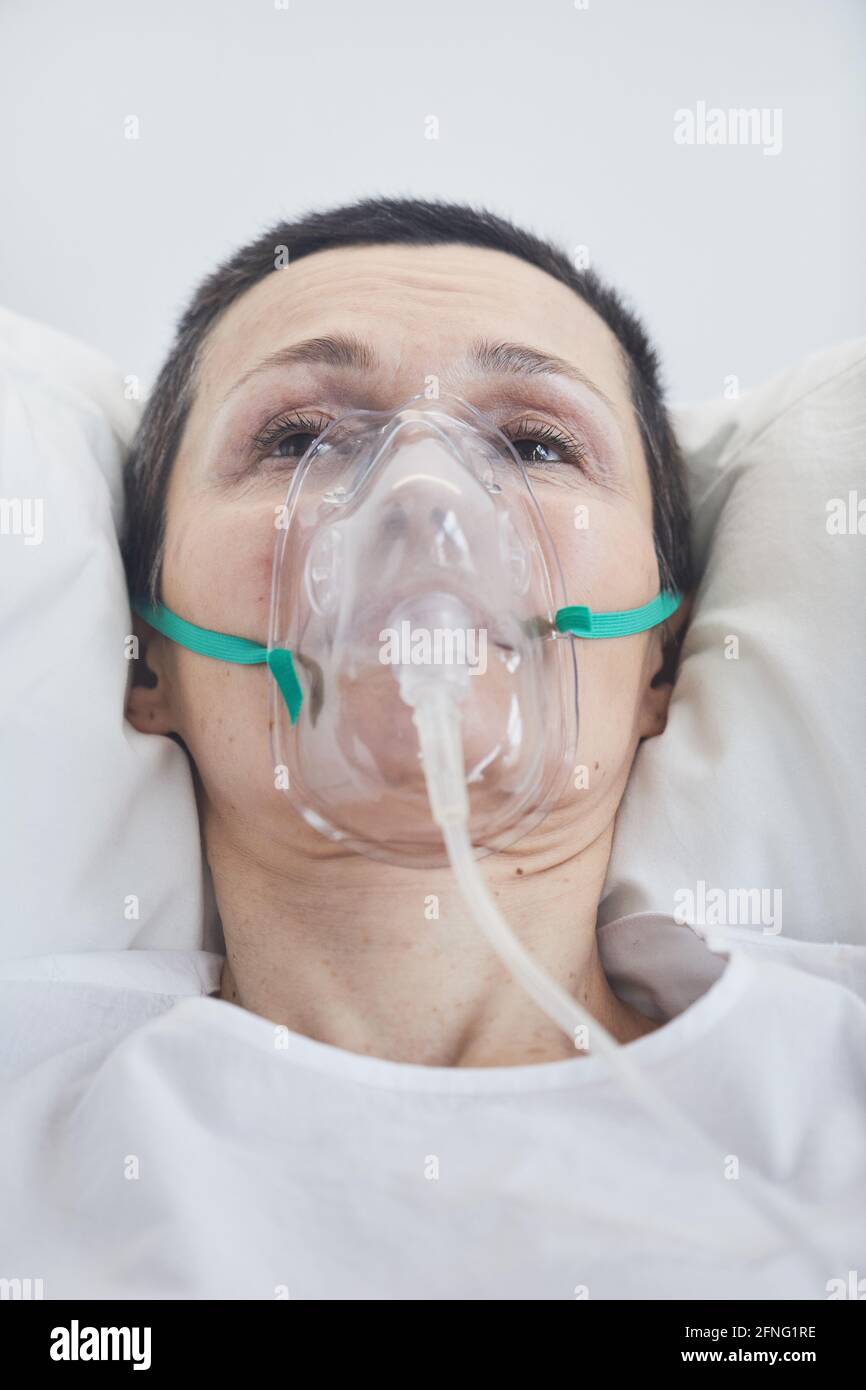 Gros plan de la femme adulte dans un masque à oxygène allongé à l'hôpital lit Banque D'Images