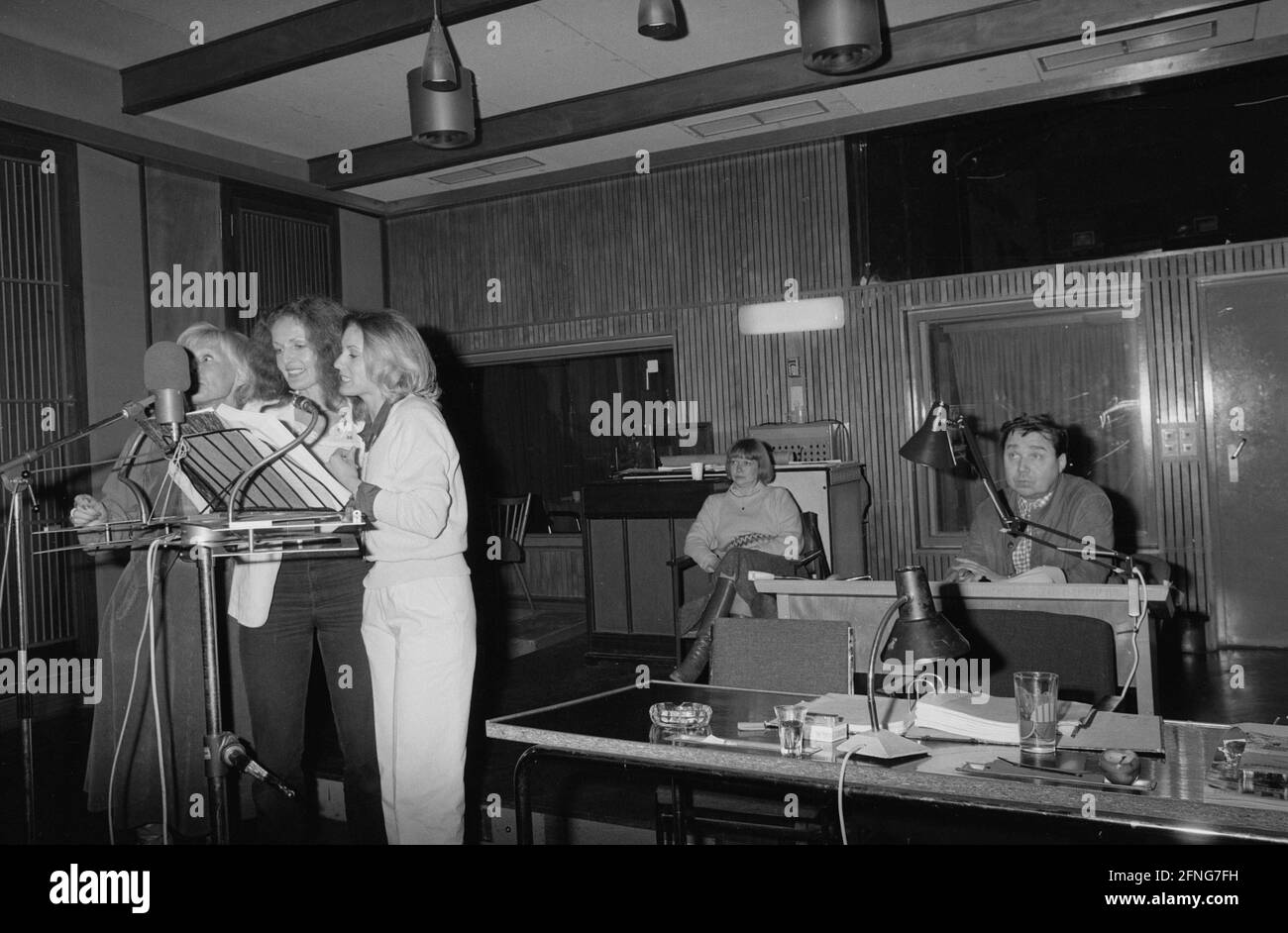 Trois femmes sont debout à un microphone. Derrière eux se trouve un homme à  un bureau. [traduction automatique] Photo Stock - Alamy