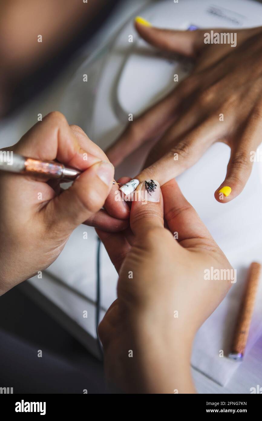 Par-dessus la récolte manucuriste méconnaissable faisant l'art des ongles pour femme dans le salon de beauté en plein jour Banque D'Images