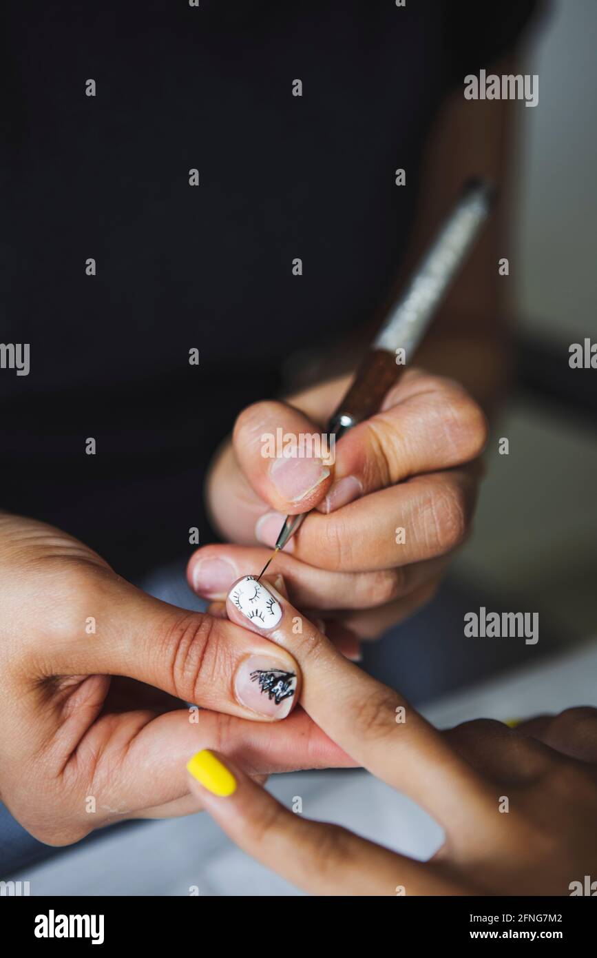 Par-dessus la récolte manucuriste méconnaissable faisant l'art des ongles pour femme dans le salon de beauté en plein jour Banque D'Images