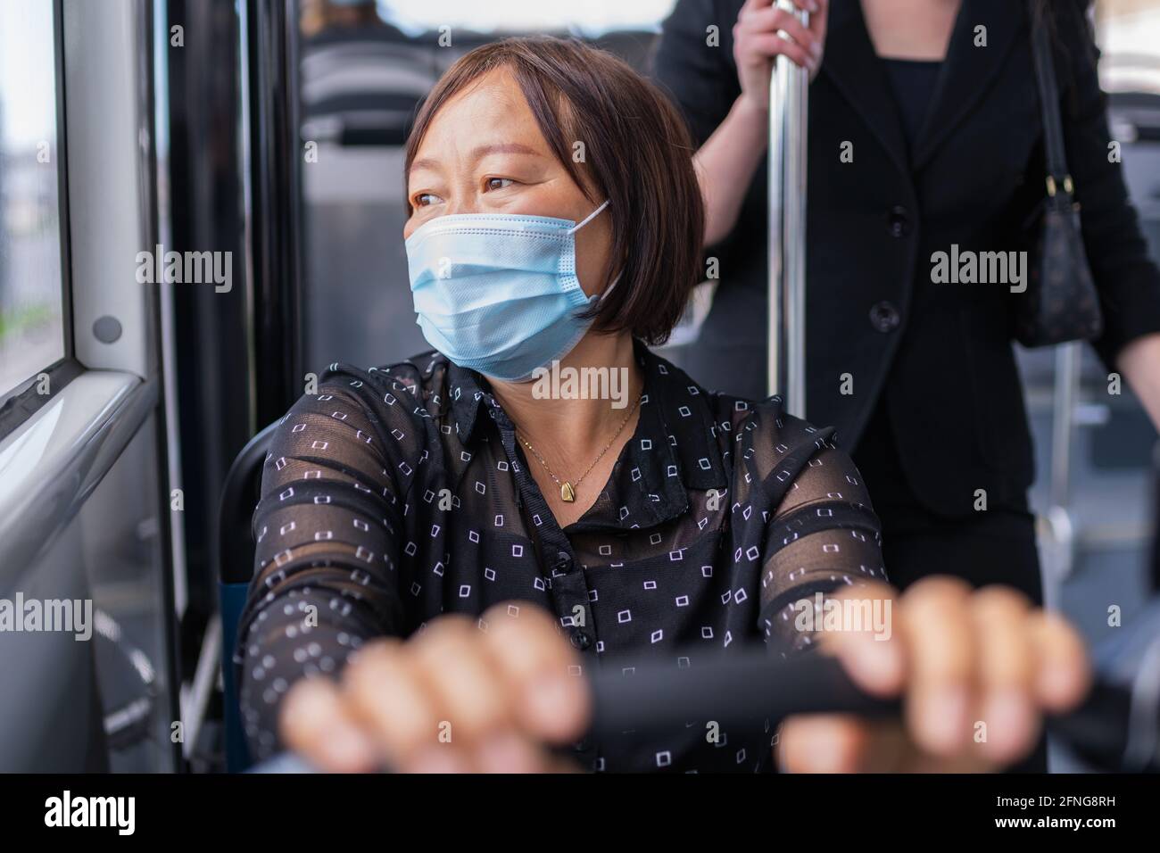 Femme asiatique assise dans un bus à l'extérieur : attention sélective. Concept de sécurité et de vacances après verrouillage. Banque D'Images