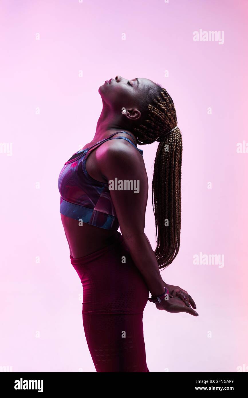 Vue latérale d'une athlète féminine ethnique avec des tresses afro et les mains clastées derrière l'entraînement du dos avec les yeux fermés Banque D'Images
