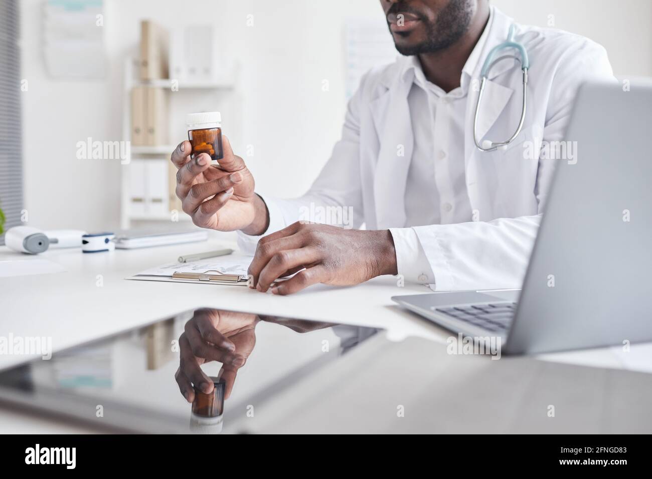 Gros plan d'un médecin africain tenant des médicaments et prescrivant au patient à la table à l'hôpital Banque D'Images