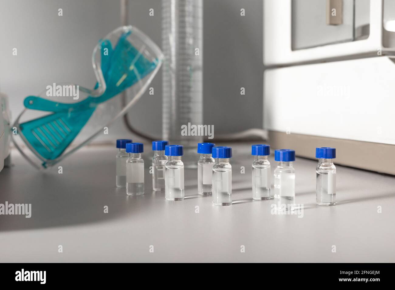 Petits flacons transparents similaires avec des liquides contre des lunettes de protection tableau dans le laboratoire de cannabis Banque D'Images
