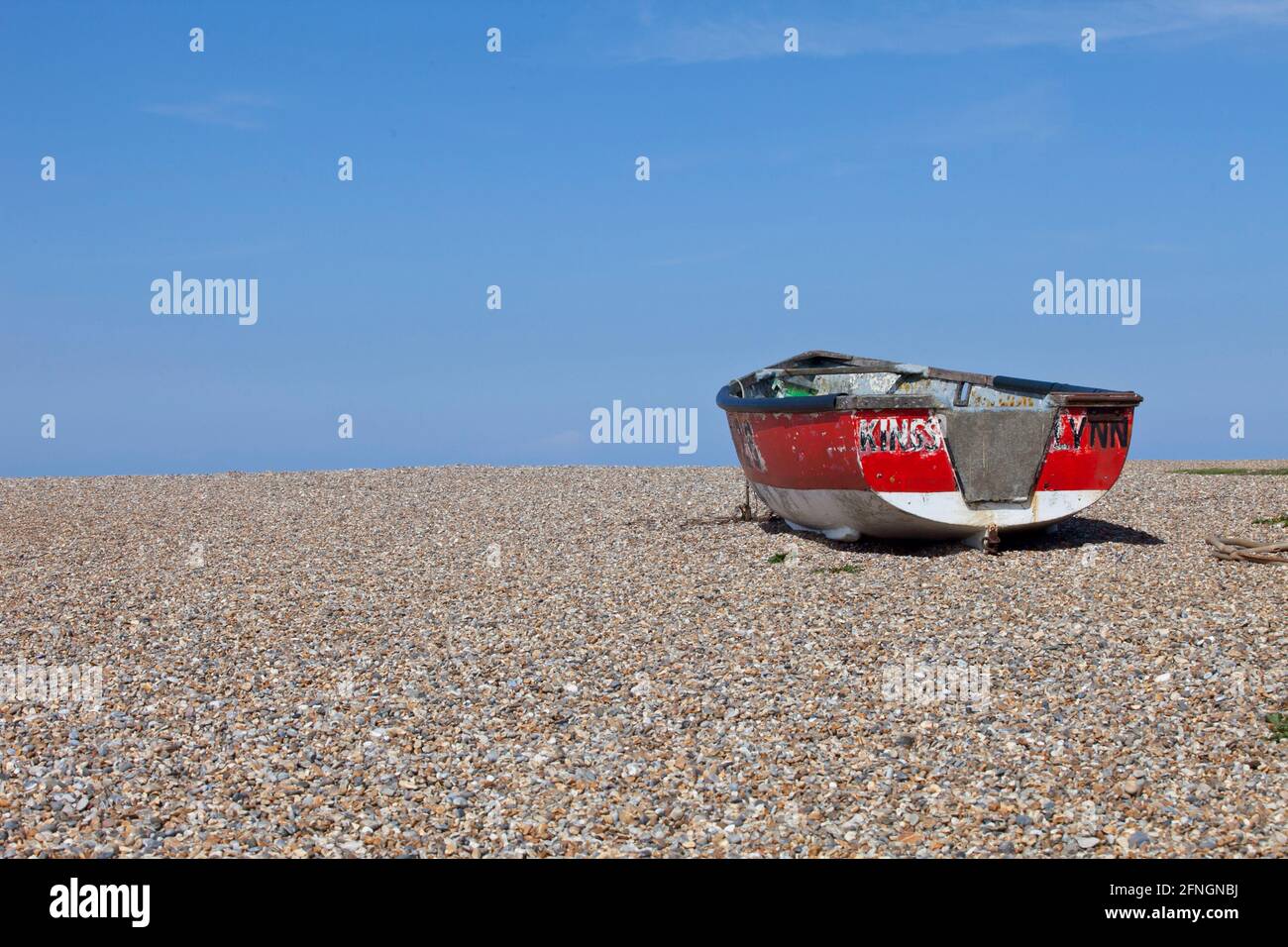 Petit bateau de pêche rouge sur la plage de galets de Norfolk Banque D'Images