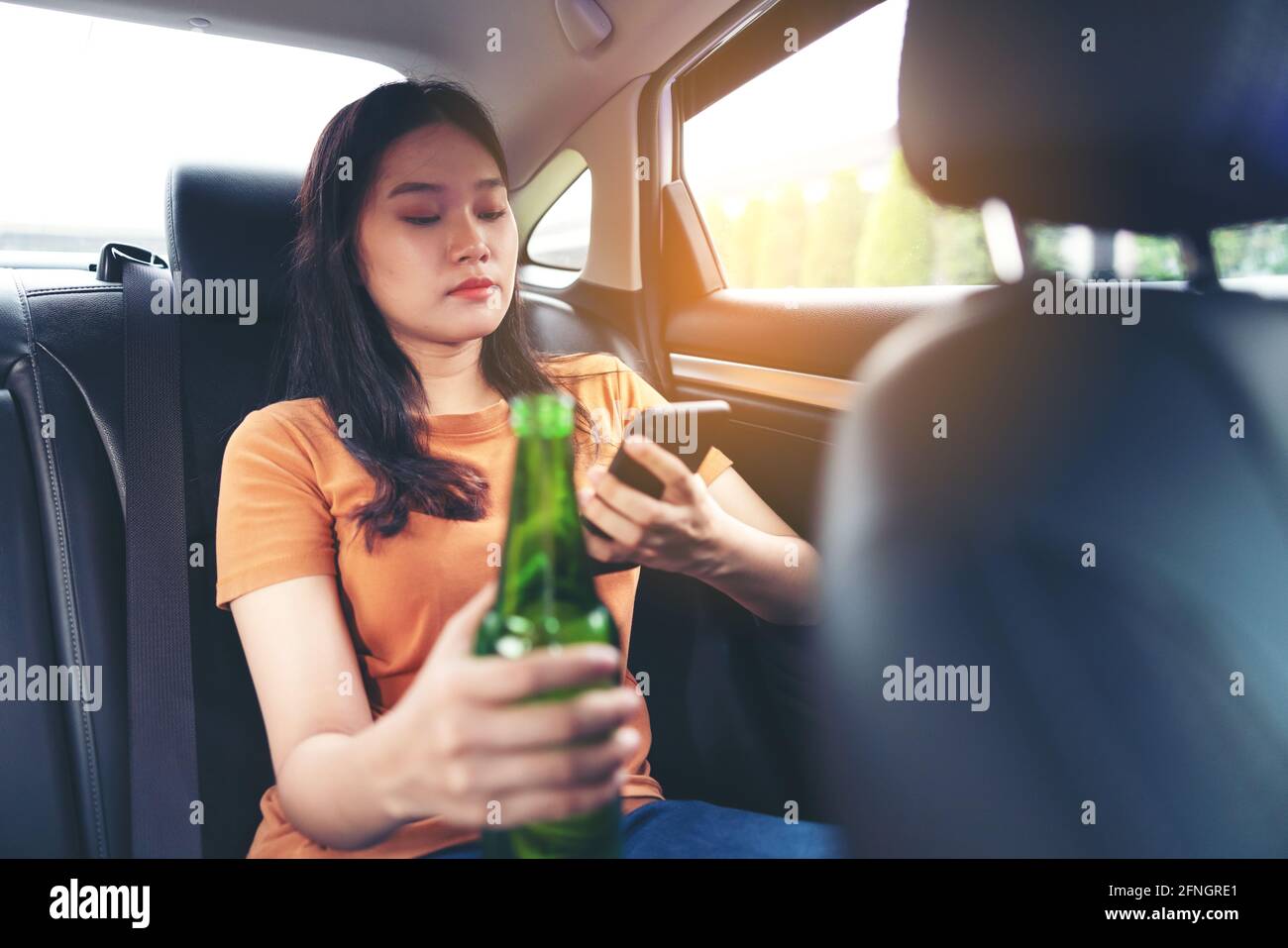 Boire une bière à la bouteille dans la voiture, filles boire de l'alcool Banque D'Images