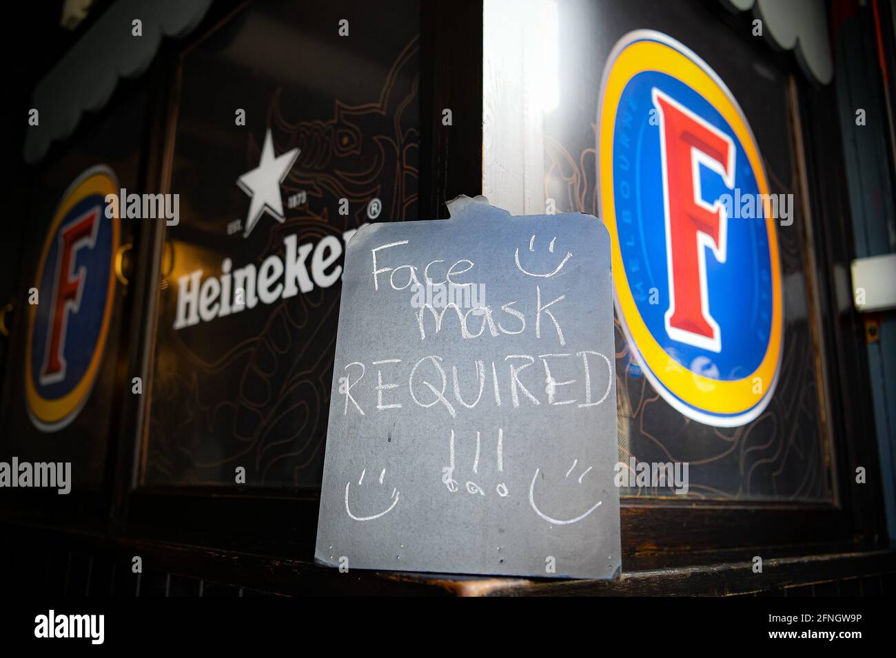 Un panneau d'exigence de masque facial à côté de la marque d'alcool au pub Borough sur St Mary's Street, Cardiff, alors que les lieux d'accueil et de divertissement intérieurs rouvrent au public suite à l'assouplissement des restrictions de verrouillage au pays de Galles. Date de la photo: Lundi 17 mai 2021. Banque D'Images