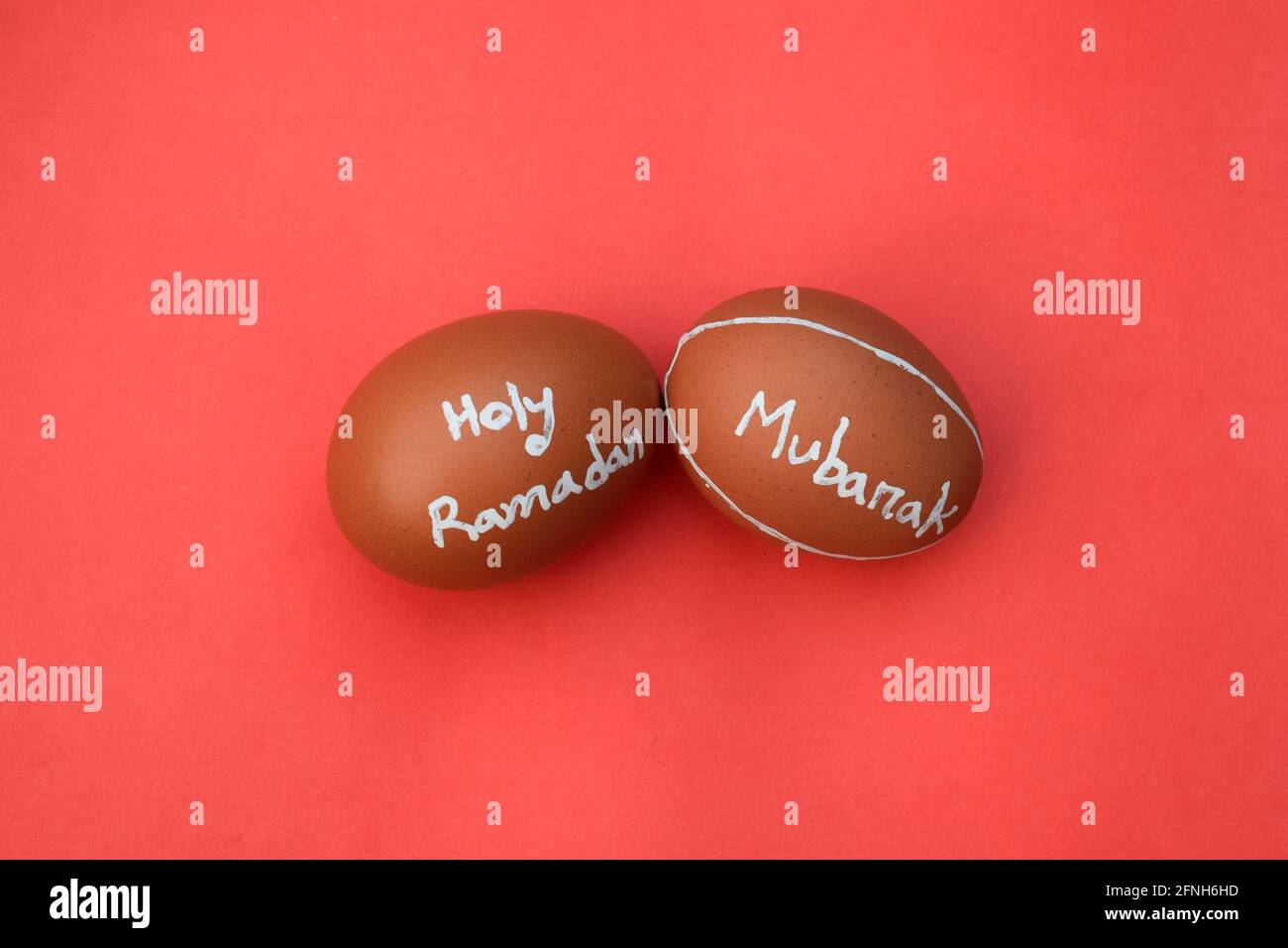 La typographie de la main du Saint Ramadan Moubarak sur l'oeuf. Arrière-plan rouge isolé. Banque D'Images