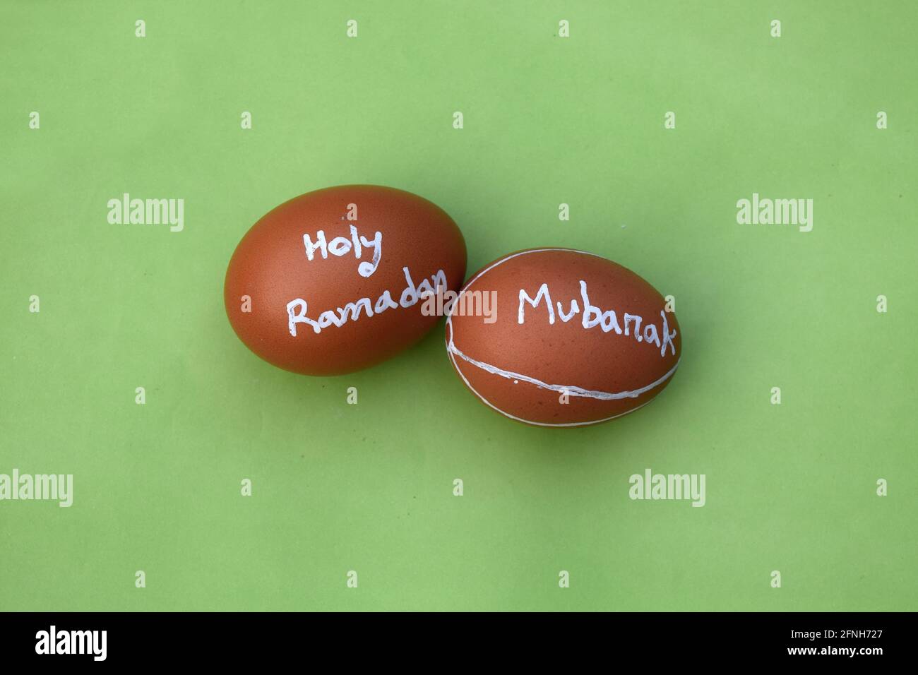 La typographie de la main du Saint Ramadan Moubarak sur l'oeuf. Arrière-plan isolé vert. Banque D'Images