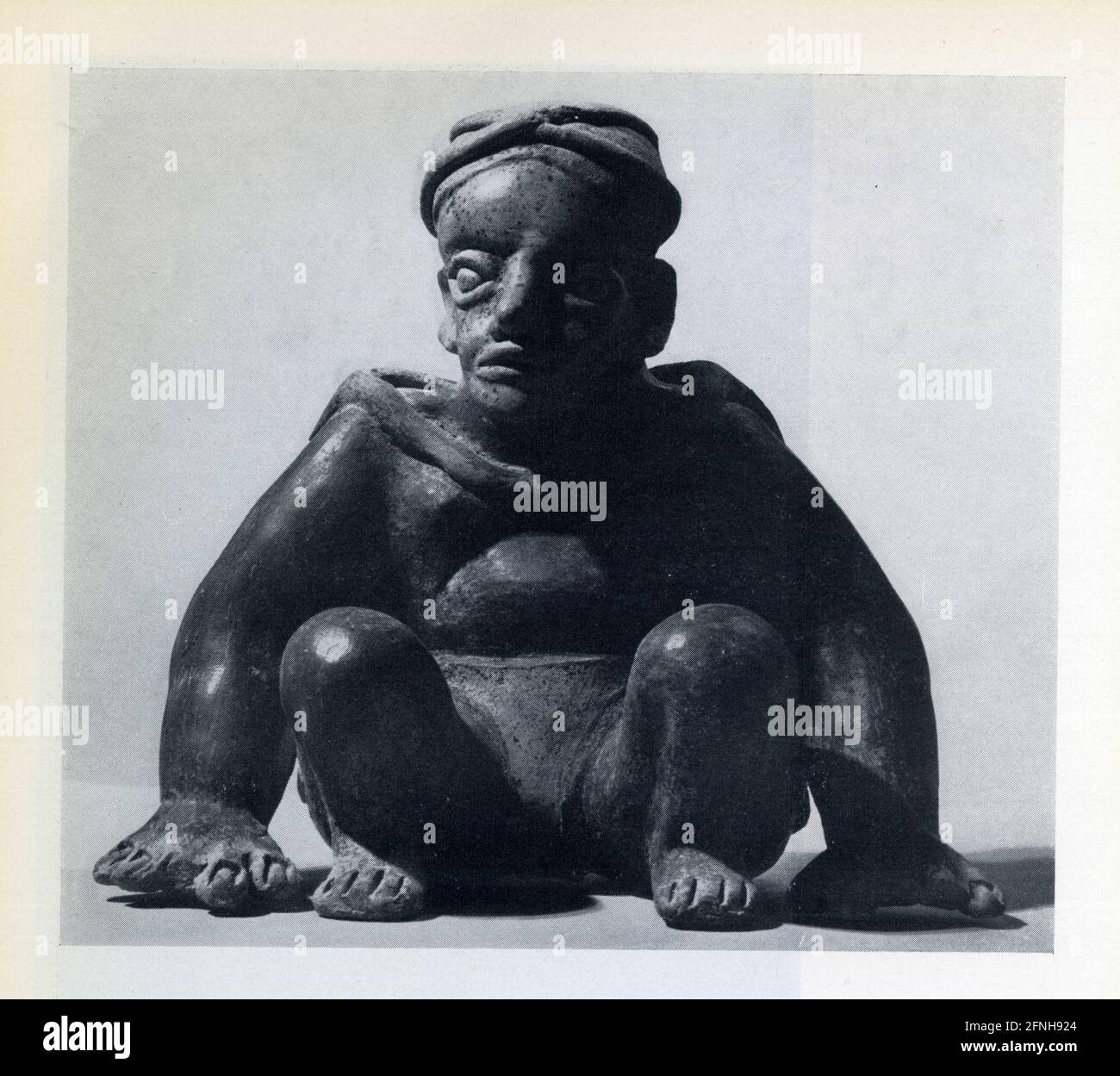 Athlète assis,les mains au sol.le dos est couvert d'une cape.Terre cuite crème polie et rouge somber polie.Époque classique.400-700 après J.C.Jalisco. Banque D'Images