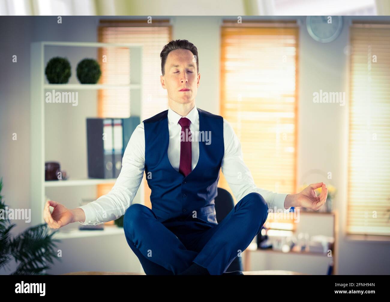 Composition d'un homme d'affaires avec les yeux fermés méditant flottant au-dessus du bureau arrière-plan Banque D'Images