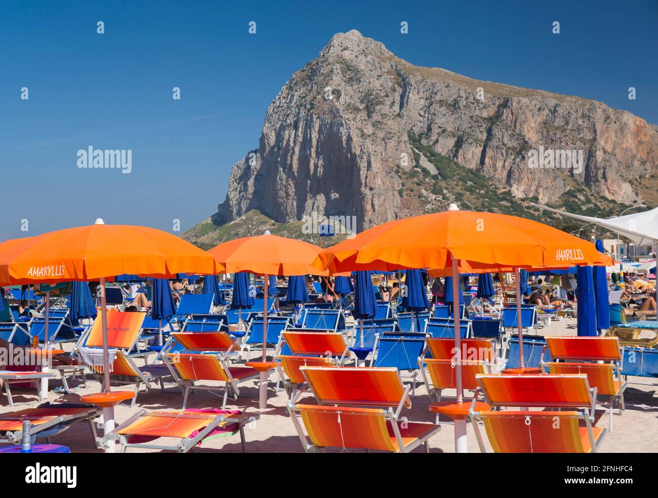 San Vito Lo Capo, Trapani, Sicile, Italie. Meubles de plage saisissants sur la rive surpeuplée, l'imposante face nord de Monte Monaco en arrière-plan. Banque D'Images