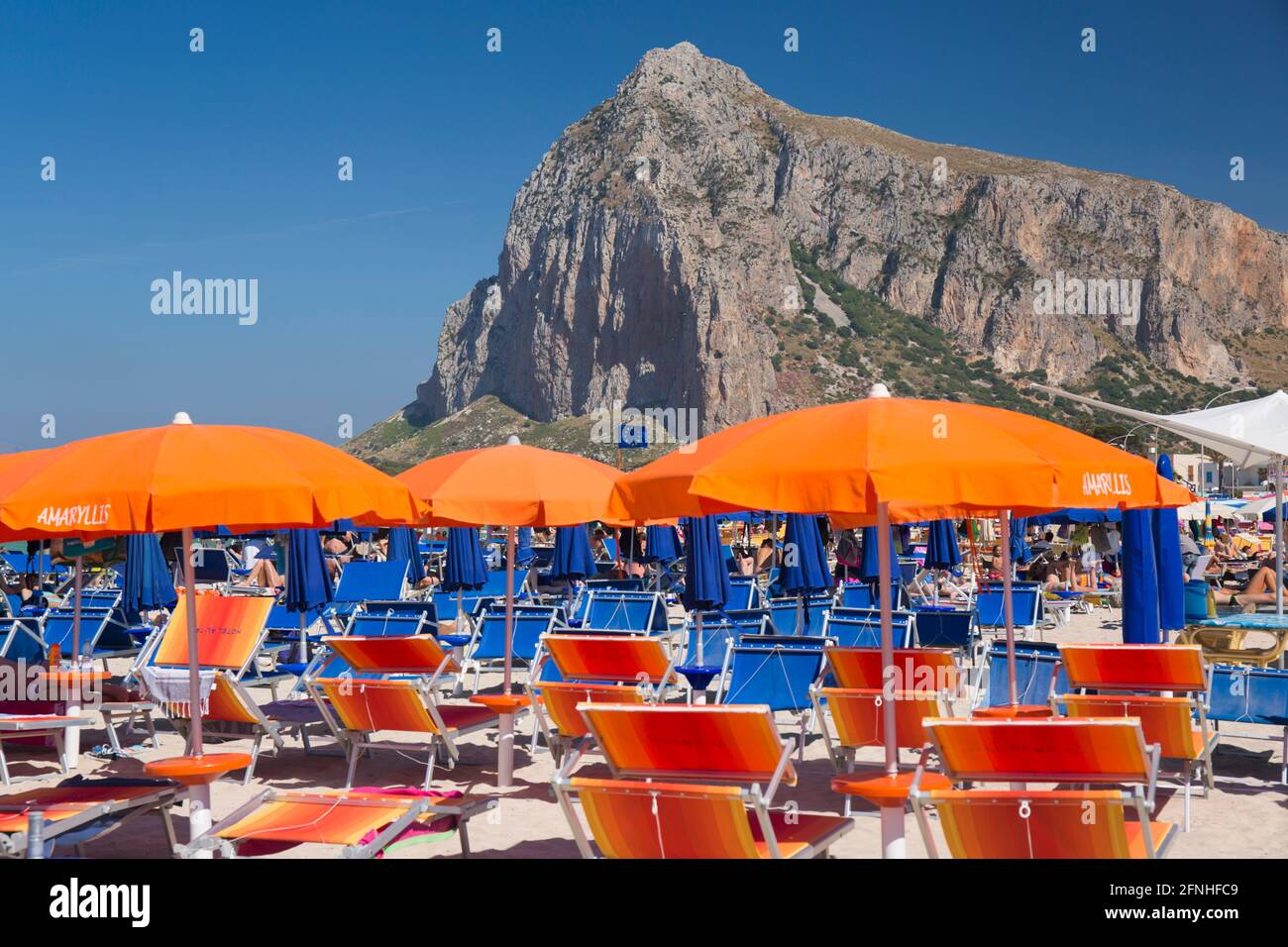 San Vito Lo Capo, Trapani, Sicile, Italie. Vue le long de la côte bondée jusqu'à l'imposante face nord de Monte Monaco, superbe mobilier de plage en premier plan. Banque D'Images