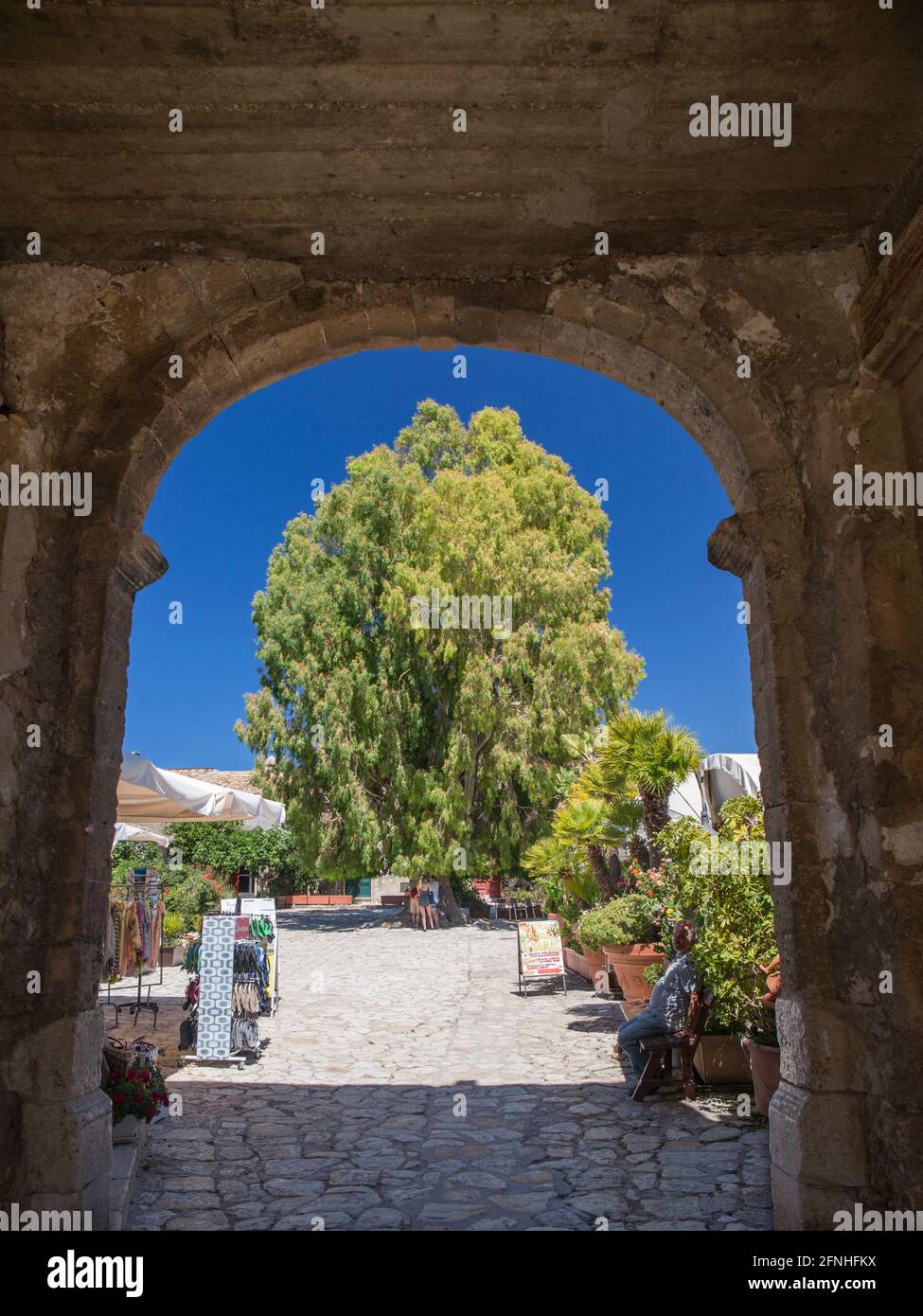 Scopello, Trapani, Sicile, Italie. Vue à travers l'arche de pierre marquant l'entrée de cour ensoleillée de l'ancien baglio. Banque D'Images