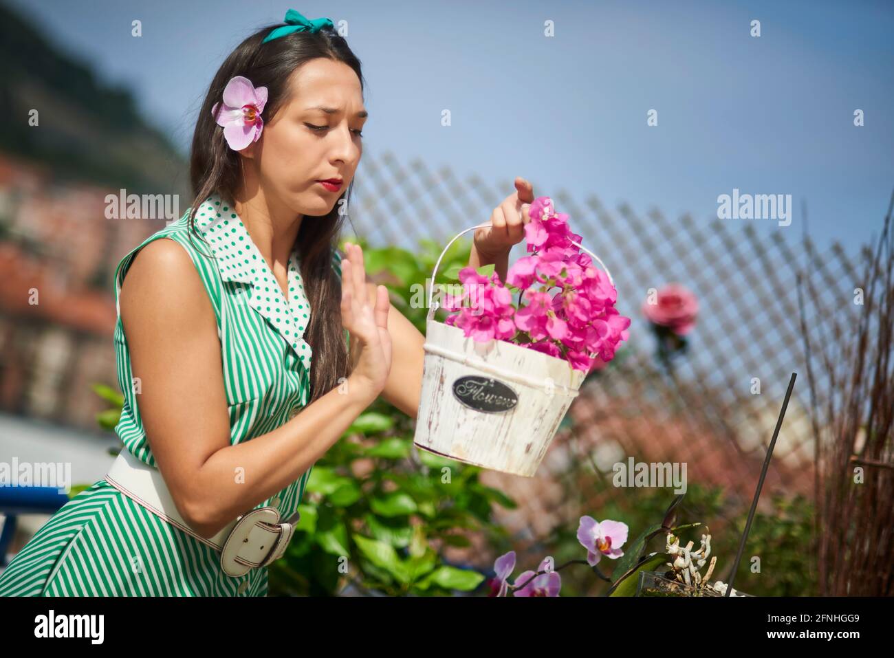 Jeune femme dans le jardin avec pot de fleurs Bougainvillea et une orchidée dans son oreille Banque D'Images