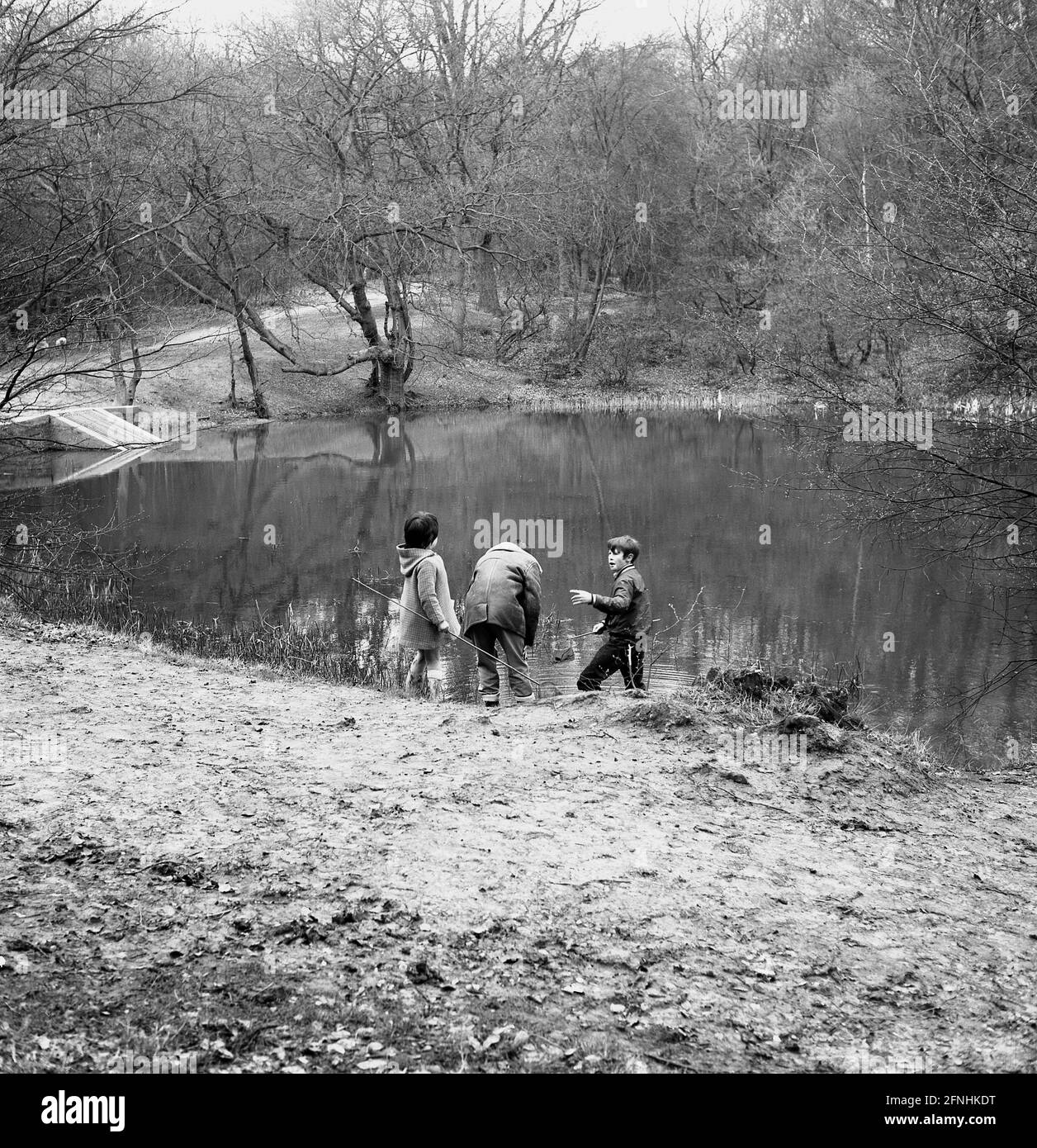 1969, historique, Epping Forest, un père avec de jeunes enfants avec des filets de pêche à Baldwin Pond, Epping, Essex, Angleterre, Royaume-Uni. Banque D'Images