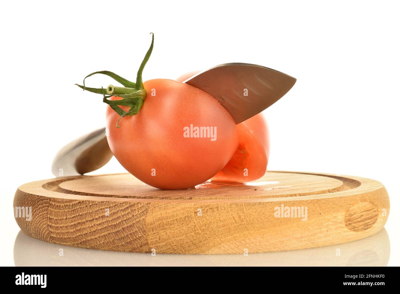 Deux moitiés d'une tomate rose vif, avec un couteau sur un plateau en bois, sur fond blanc. Banque D'Images