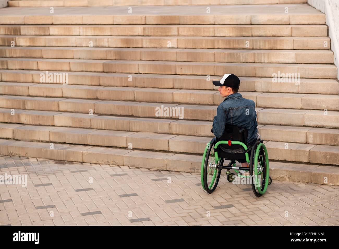 un jeune handicapé en fauteuil roulant ne peut pas entrer dans les escaliers. Environnement accessible pour les personnes handicapées Banque D'Images