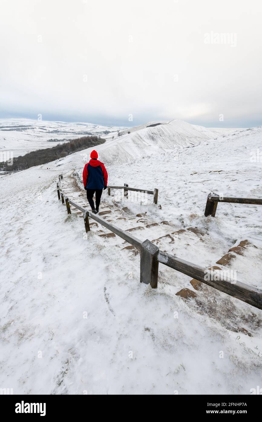 Homme en manteau rouge en hiver en marchant vers Rushup Edge depuis MAM Tor, Peak District, Derbyshire Banque D'Images