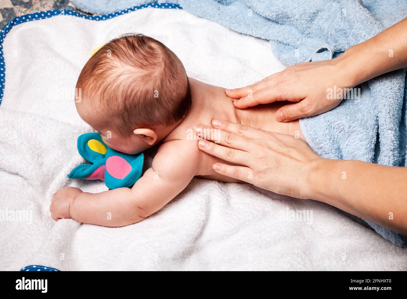 Bébé de cinq mois recevant la thérapie de massage à la maison pendant le verrouillage. Un thérapeute manuel ostéopathique ou chiropractique manipule le dos de l'enfant Banque D'Images