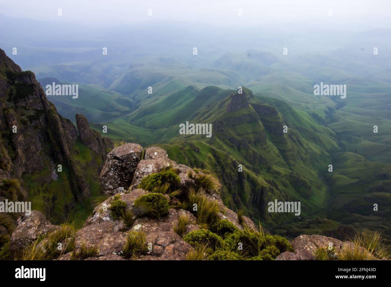 Vue depuis les hauts sommets des montagnes du Drakensberg à la frontière entre l'Afrique du Sud et le Lesotho, avec les collines verdoyantes et les montagnes en contrebas Banque D'Images