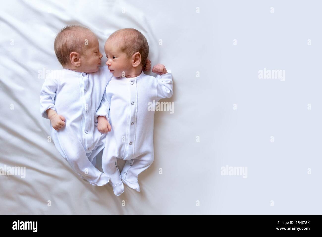 Nouveau Nes Jumeaux Sur Le Lit Dans Les Bras De Leurs Parents Sur Fond Blanc Style De Vie Emotions Des Enfants Photo Stock Alamy