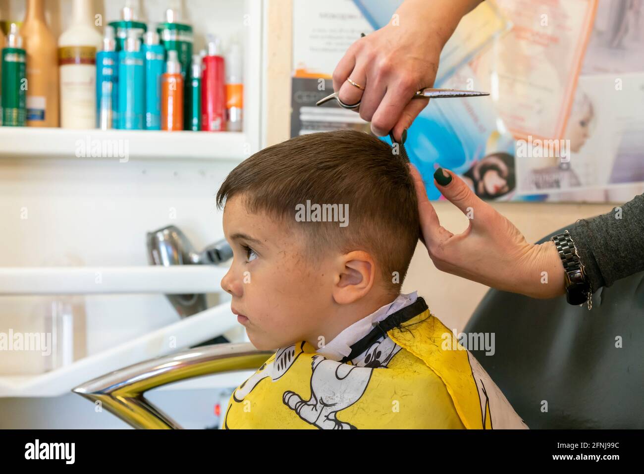 Petit garçon ayant une coupe de cheveux au salon de coiffure..enfants  coiffeur avec des ciseaux et le peigne est de couper petit garçon. Un  adorable garçon d'âge préscolaire Photo Stock - Alamy