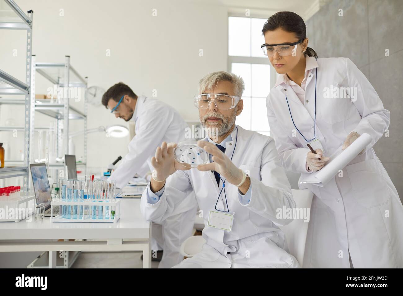 Deux scientifiques masculins et féminins analysent des échantillons travaillant avec des produits chimiques dans un laboratoire. Banque D'Images