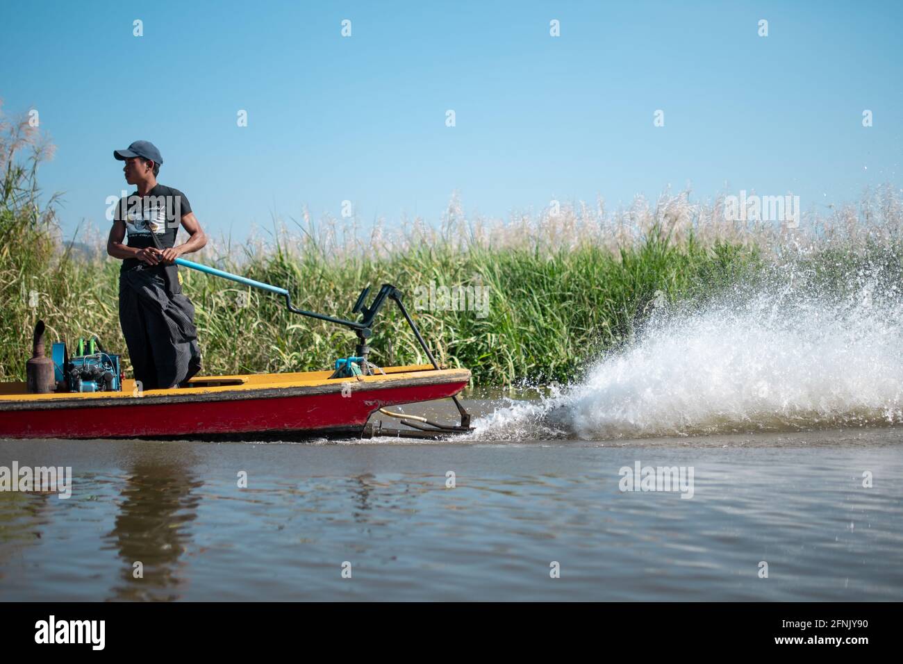 Etat de Shan, Myanmar - janvier 7 2020 : un capitaine local à Longyi conduit un bateau traditionnel au bord des jardins flottants dans les canaux du lac Inle, Nyaung S. Banque D'Images