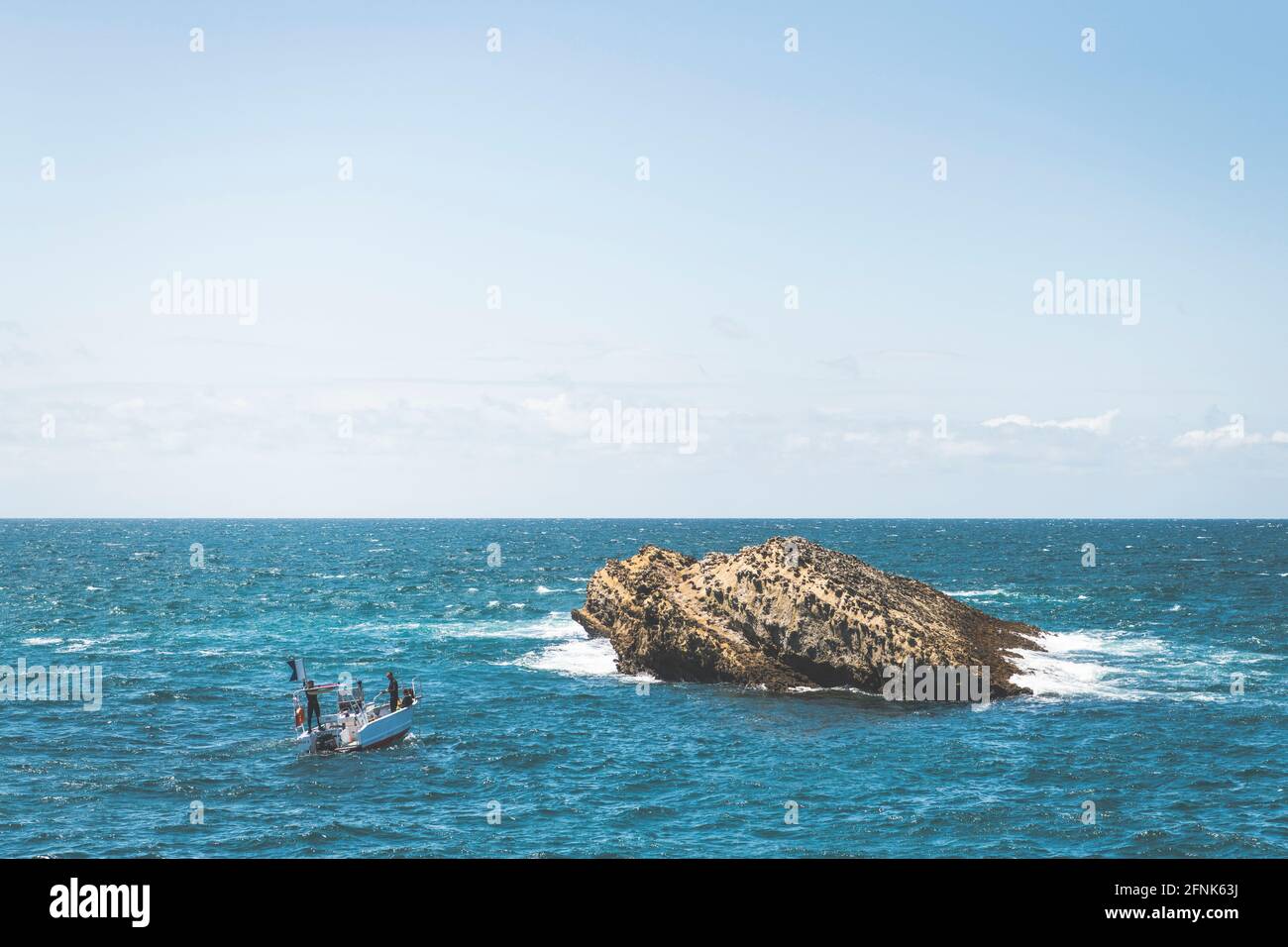 Un petit bateau se dirige vers un rocher Banque D'Images