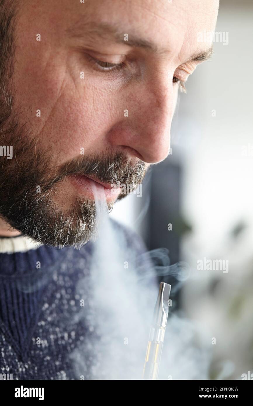 homme vaporant du distillat de cannabis avec un stylo de vape Banque D'Images