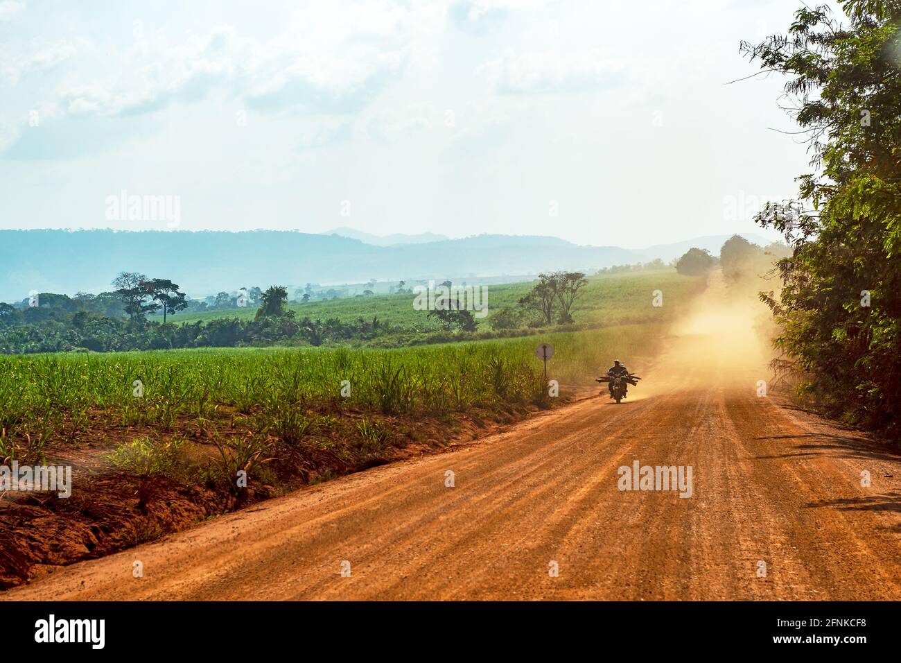 Pilote de moto sur une route poussiéreuse en Afrique Banque D'Images