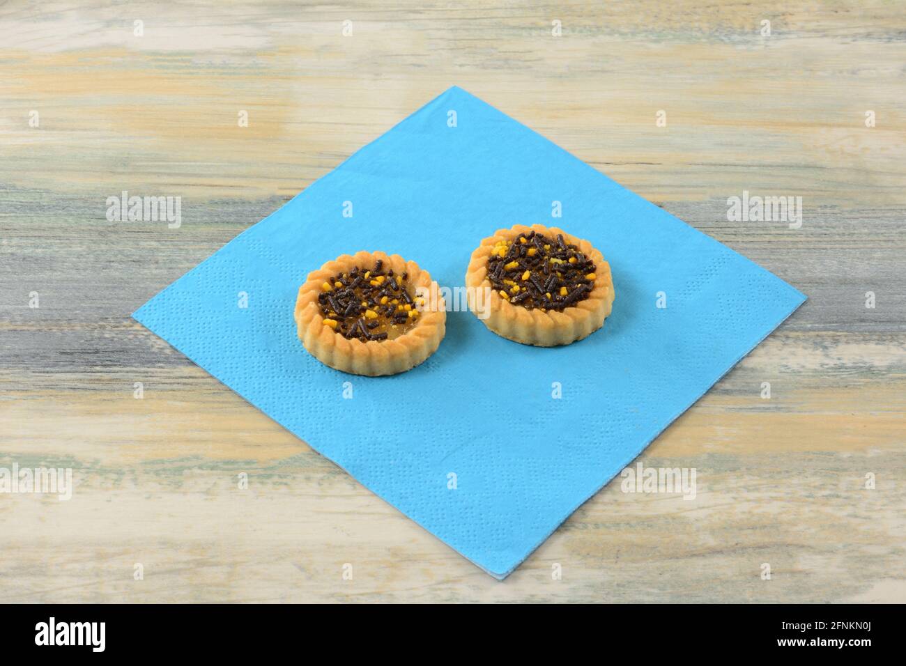 Deux tartelettes aux agrumes saupoudrées de cacao et d'orange dessus de la serviette bleue Banque D'Images