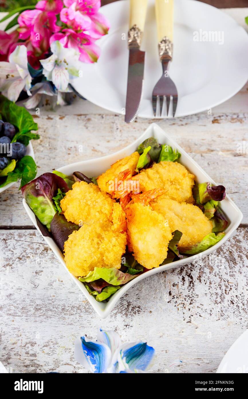 Crevettes panées frites avec salade verte et table. Banque D'Images