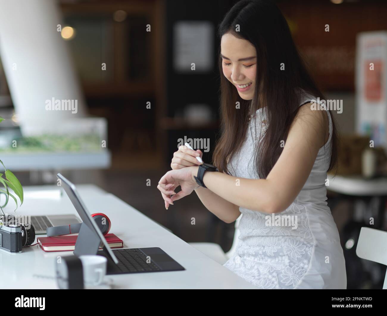 Portrait d'une femme regardant une montre intelligente tout en travaillant en collaboration espace de travail Banque D'Images