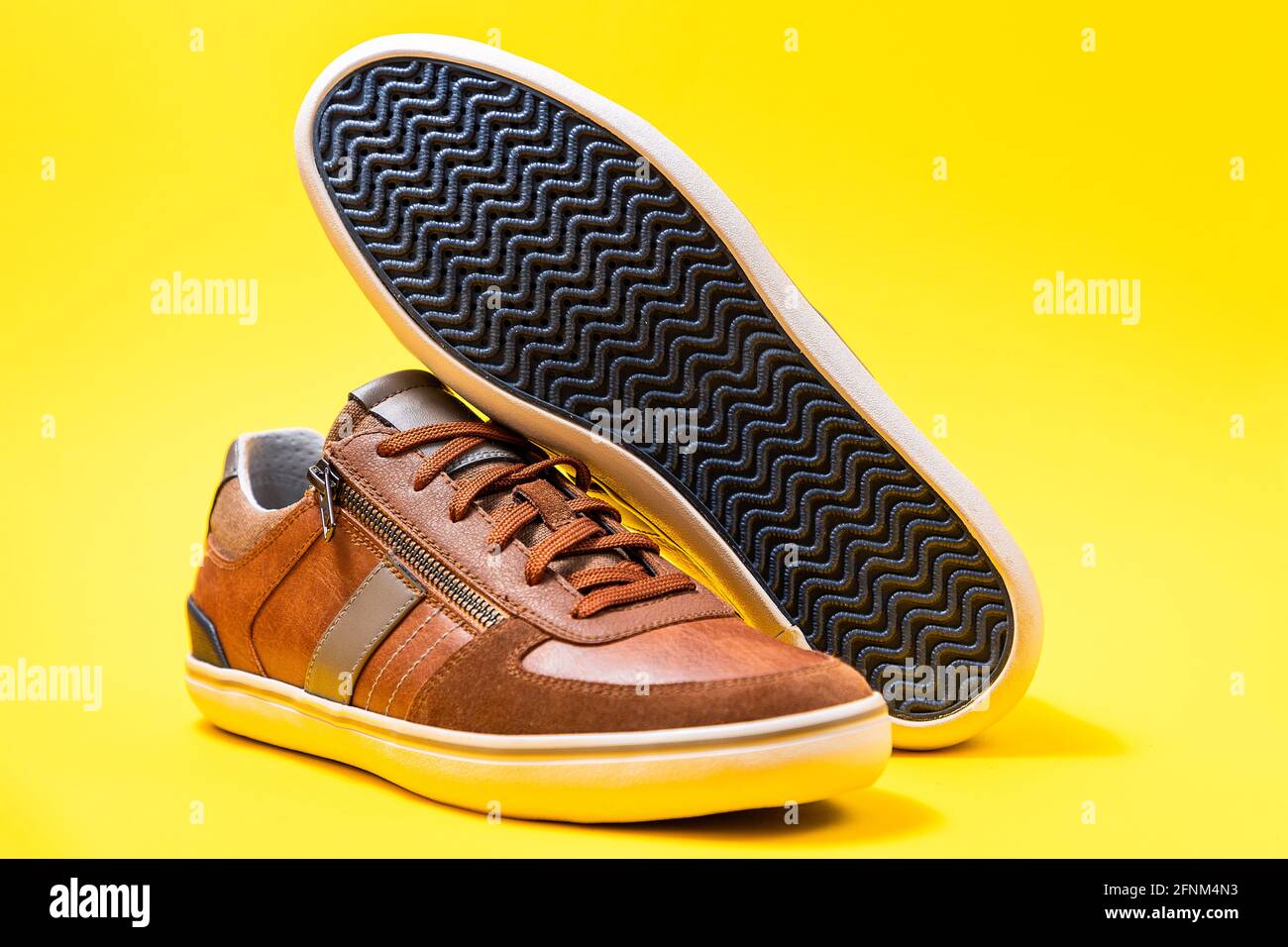 Nouvelle paire de sneakers pour homme en cuir marron joliment agentées sur  fond jaune. Nettoyer la semelle de chaussure. Gros plan Photo Stock - Alamy