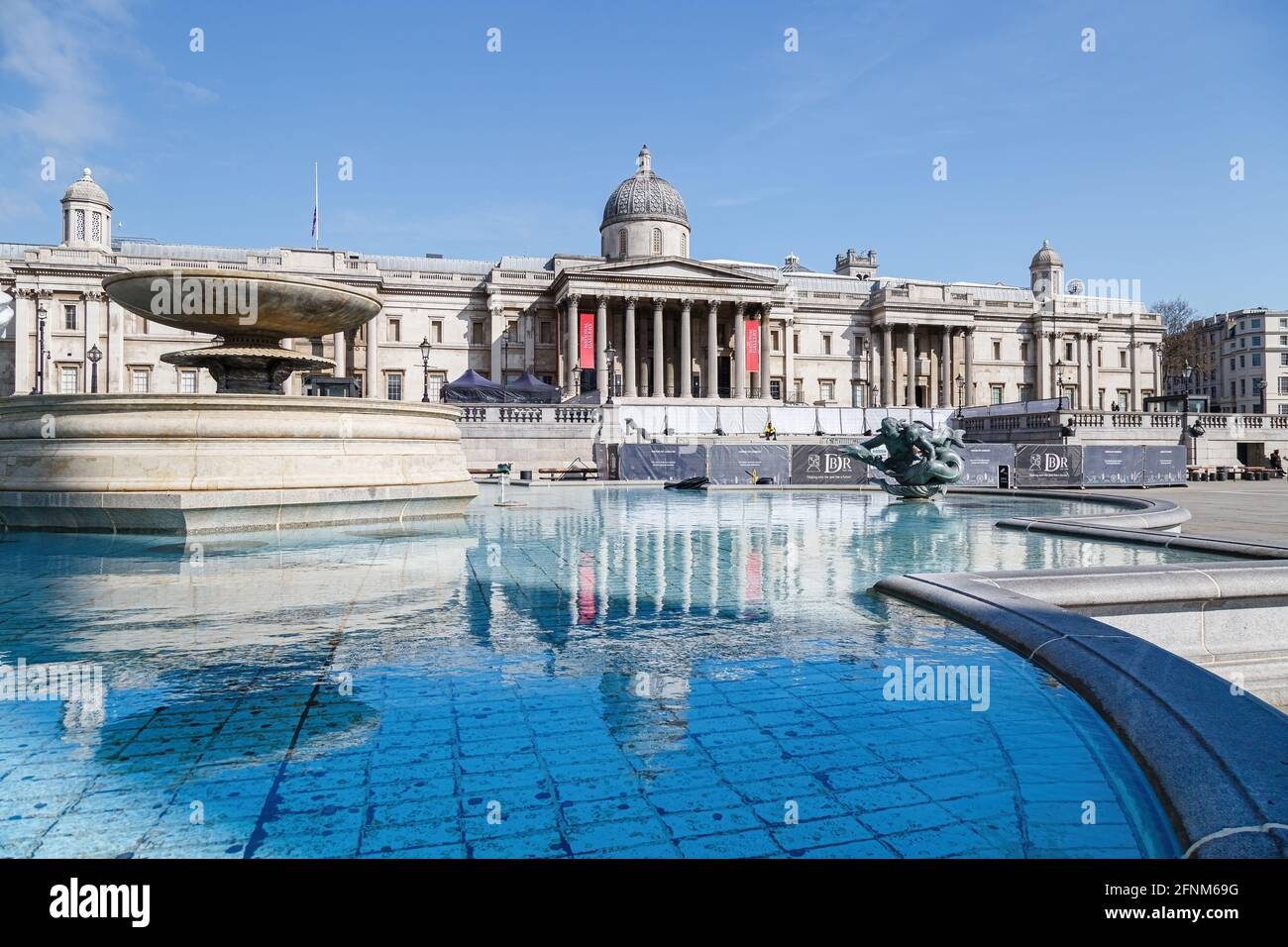 La Galerie nationale se reflète dans les eaux encore bleues de l'une des fontaines de Trafalgar Square, qui remplit l'image au premier plan. Banque D'Images