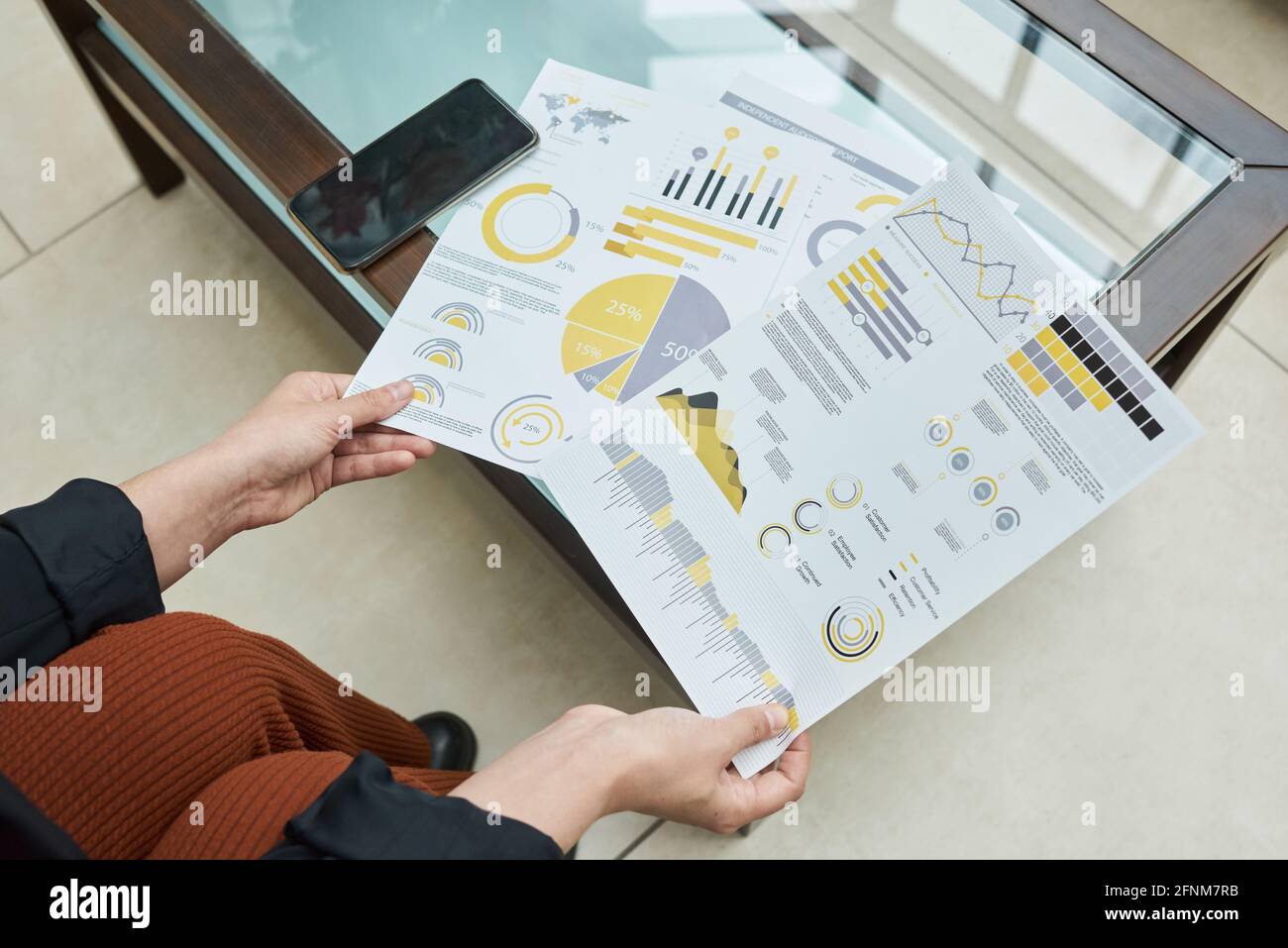 Gros plan d'une femme d'affaires assise à la table et examinant les finances rapport avec graphiques Banque D'Images