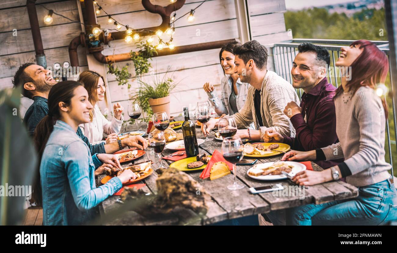 Les jeunes dînent et s'amusent à boire du vin rouge ensemble Dîner sur le toit du balcon - Happy Friends mangeant bbq restauration sur le patio du restaurant Banque D'Images