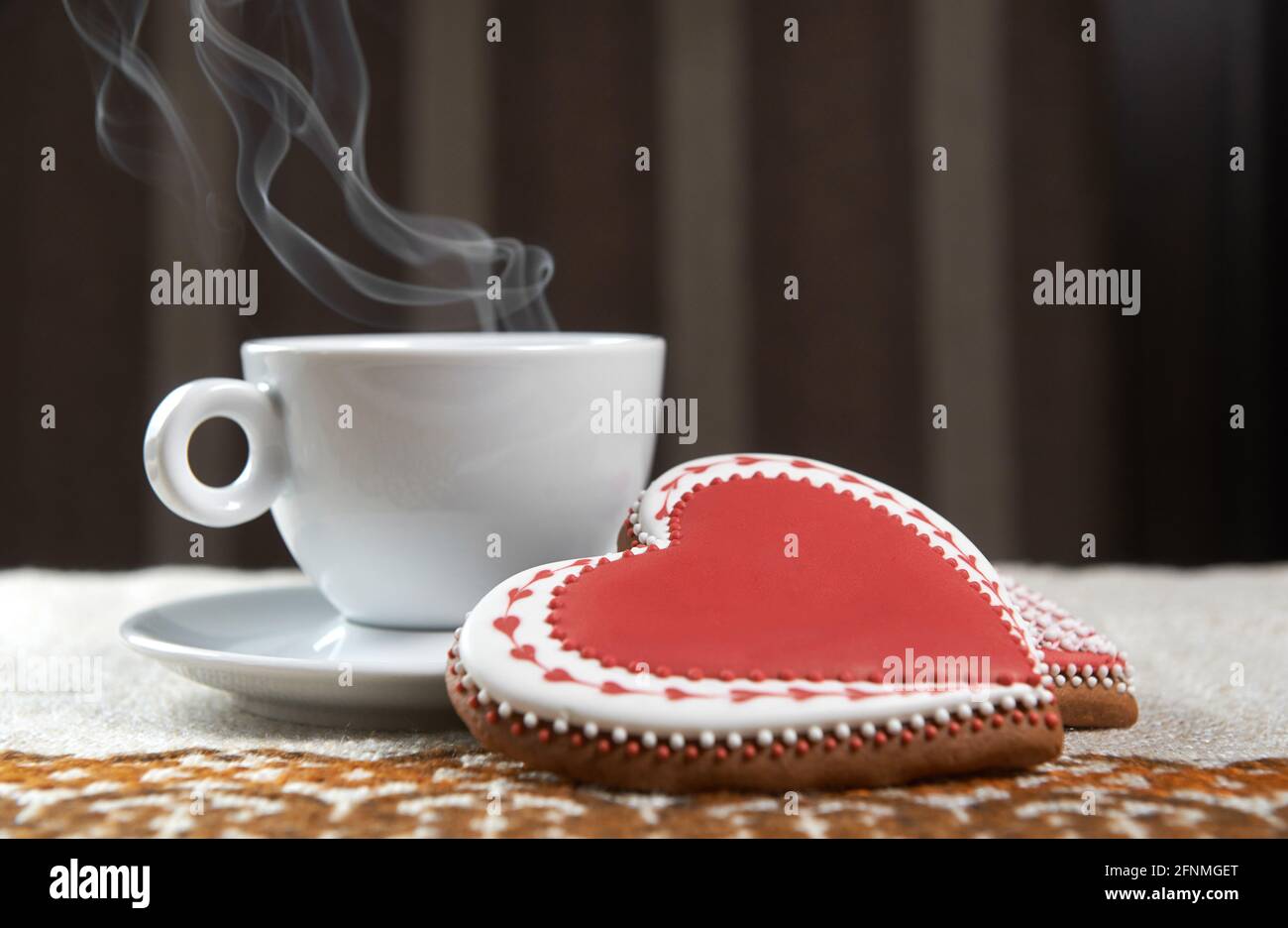 Pour vous. Café cuit à la vapeur dans une tasse sur la table à côté de deux biscuits en forme de coeur de pain d'épice Banque D'Images