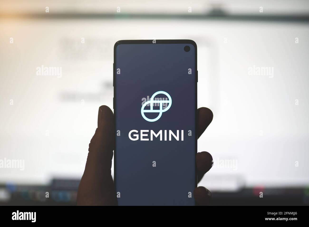 SWANSEA, Royaume-Uni - 2 MAI 2021: Homme tenant un smartphone avec le logo de l'application Gemini avec un arrière-plan flou du site Web. Bourse de crypto-monnaies, plate-forme portefeuille Banque D'Images