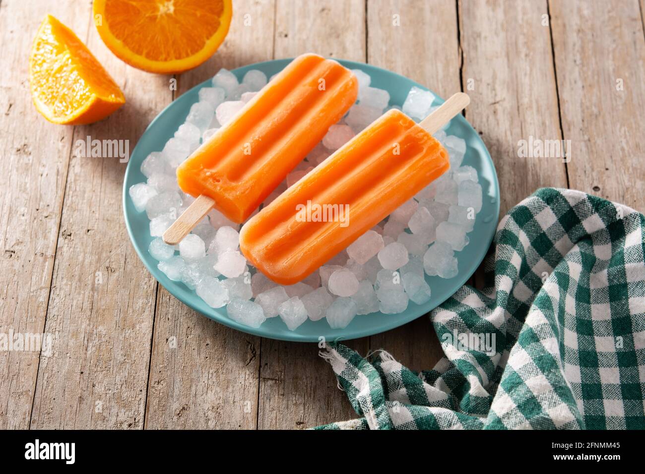 Pop-sicles orange sur plaque bleue sur table en bois Banque D'Images