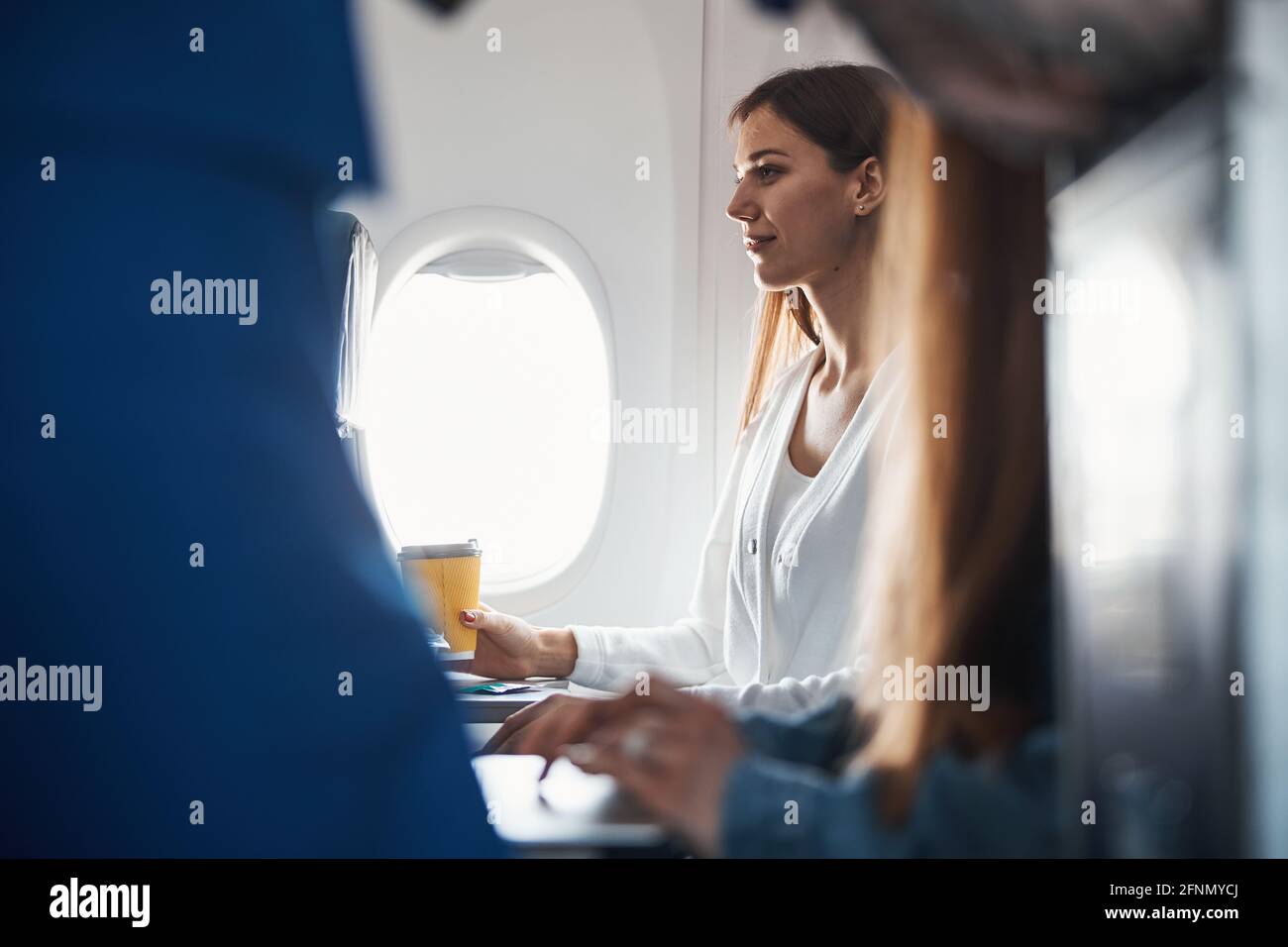 Une femme assise avec un café sur son siège d'avion Banque D'Images