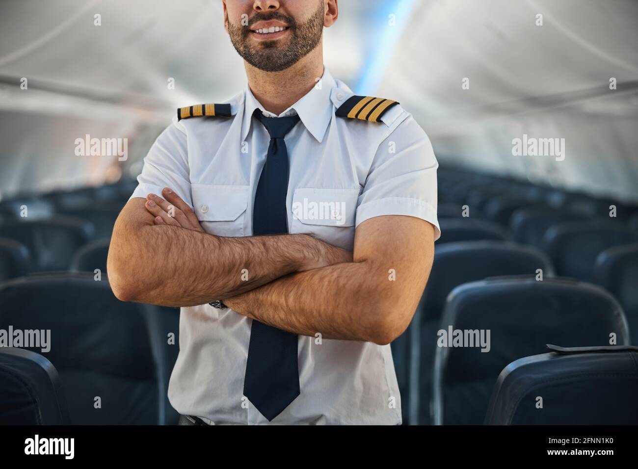 Homme confiant pilote gardant ses bras croisés dans l'avion Banque D'Images