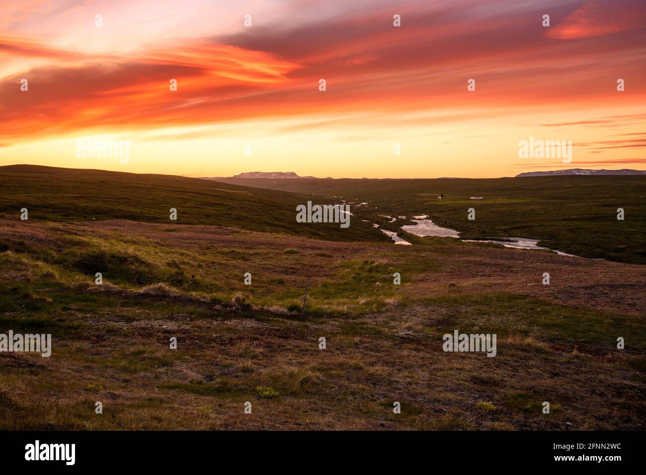 Vallée de rivière verte avec sous un ciel orange spectaculaire à minuit en été Banque D'Images